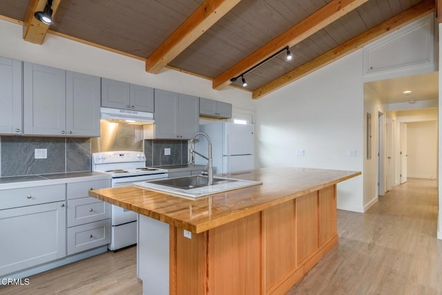 kitchen featuring a sink, wood counters, an island with sink, white appliances, and under cabinet range hood