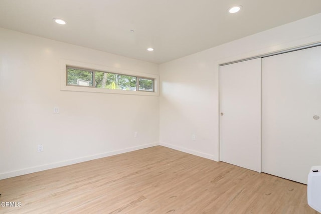 unfurnished bedroom with baseboards, a closet, light wood-type flooring, and recessed lighting