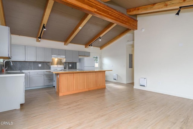 kitchen with a center island, gray cabinets, freestanding refrigerator, a sink, and beamed ceiling