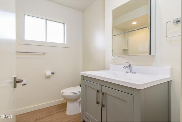 bathroom with toilet, recessed lighting, wood finished floors, vanity, and baseboards