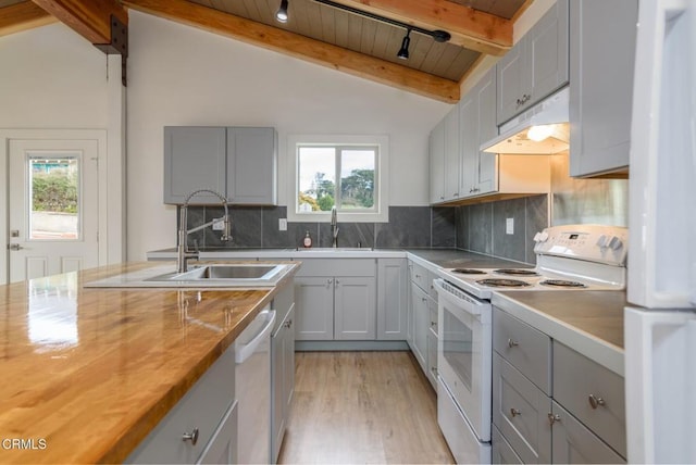 kitchen featuring white appliances, lofted ceiling with beams, wood counters, under cabinet range hood, and a sink