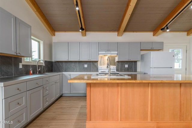 kitchen featuring butcher block countertops, freestanding refrigerator, a sink, and backsplash