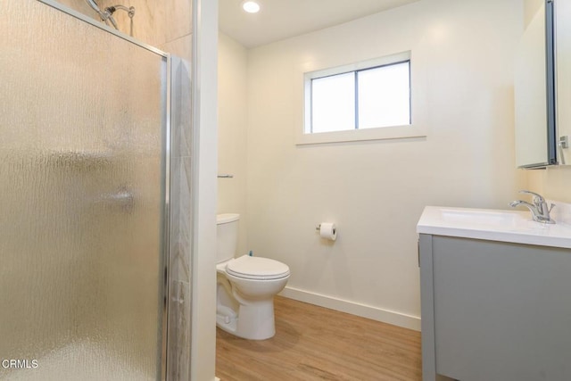 full bathroom featuring toilet, a stall shower, vanity, wood finished floors, and baseboards