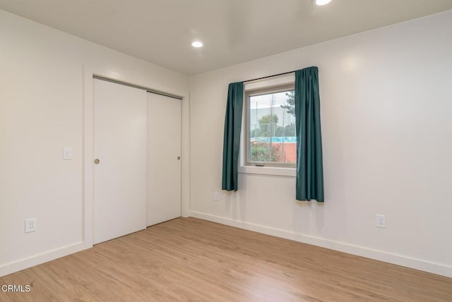 unfurnished bedroom with baseboards, a closet, light wood-style flooring, and recessed lighting