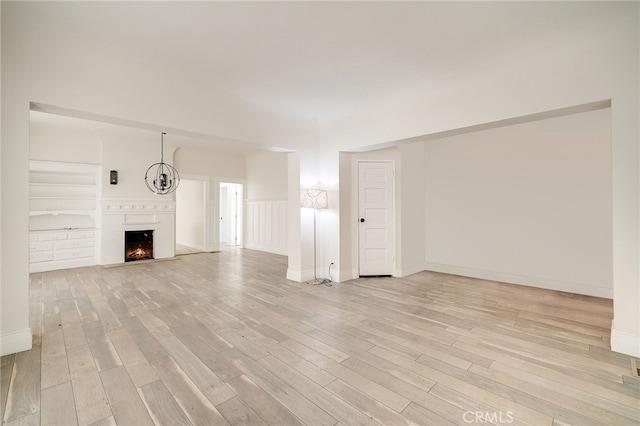 unfurnished living room with light hardwood / wood-style floors and built in shelves