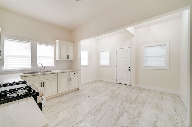 kitchen featuring gas stove, sink, and light stone counters