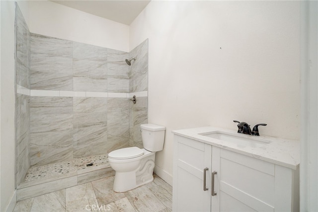 bathroom featuring vanity, toilet, and a tile shower