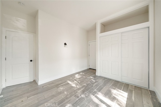 unfurnished bedroom featuring light hardwood / wood-style flooring and a closet