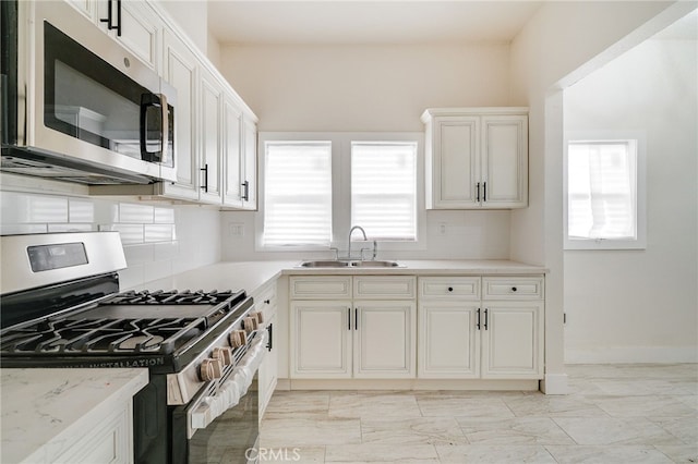 kitchen featuring white cabinetry, stainless steel appliances, light stone countertops, and sink