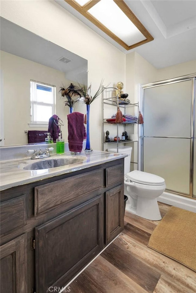 bathroom featuring a shower with door, vanity, hardwood / wood-style floors, and toilet