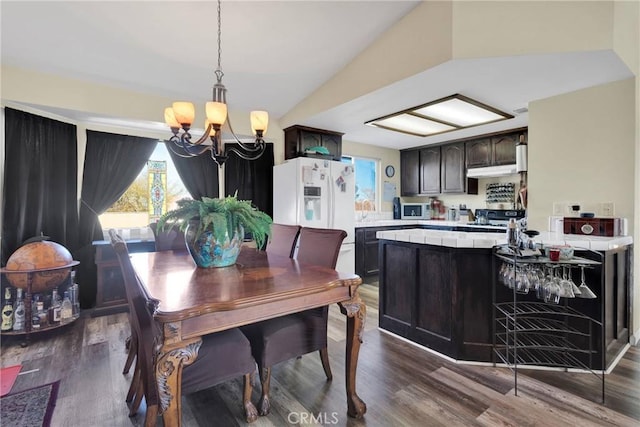 dining space featuring lofted ceiling, dark hardwood / wood-style floors, and an inviting chandelier