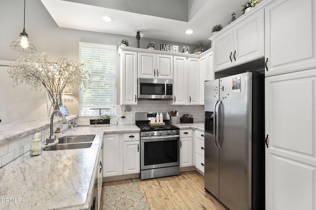 kitchen with sink, decorative light fixtures, stainless steel appliances, and white cabinets