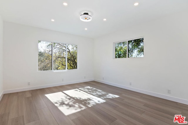 empty room with hardwood / wood-style flooring and a healthy amount of sunlight