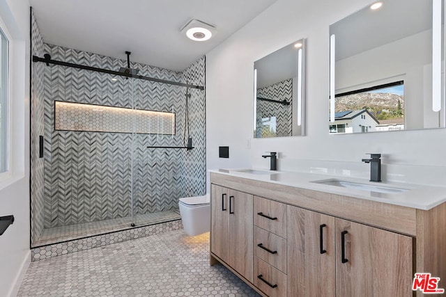 bathroom featuring vanity, a tile shower, tile patterned floors, and toilet