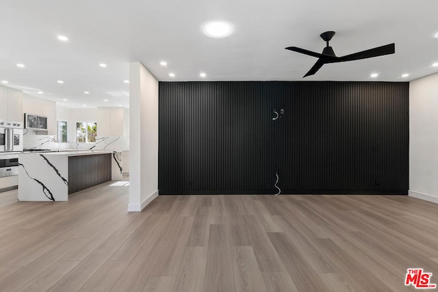 unfurnished room with ceiling fan and light wood-type flooring