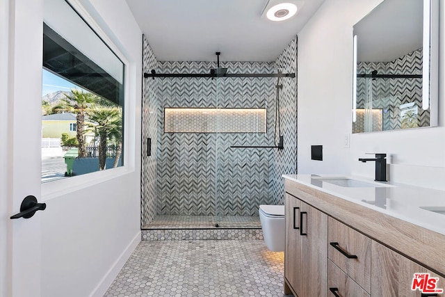 bathroom featuring vanity, tiled shower, tile patterned floors, and toilet