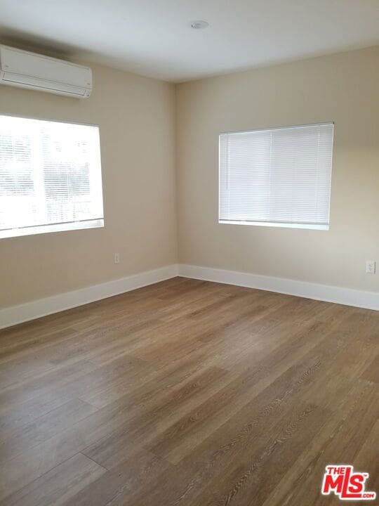 empty room with wood-type flooring and a wall mounted AC