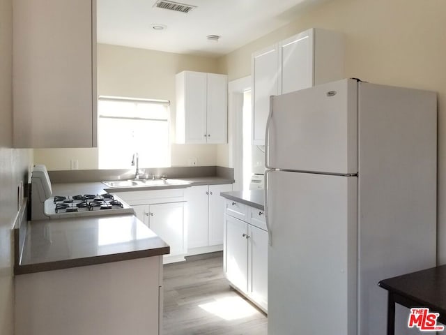 kitchen with light hardwood / wood-style floors, sink, white fridge, and white cabinets