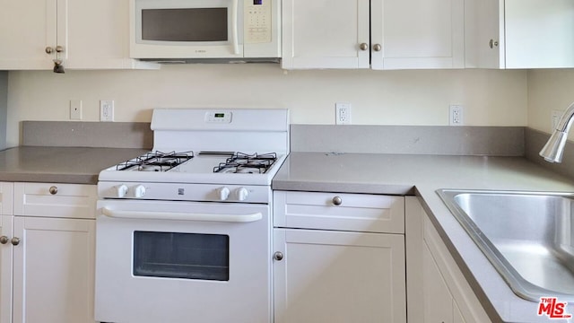 kitchen with sink, white appliances, and white cabinets