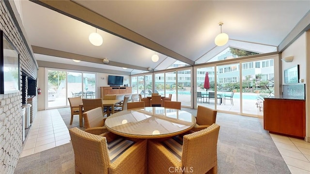 dining area with lofted ceiling, a wealth of natural light, and light tile patterned floors