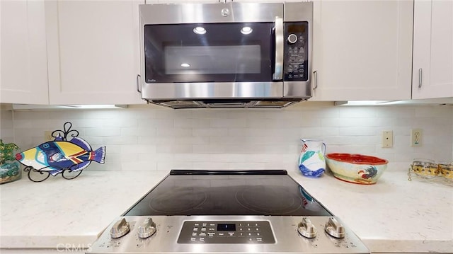 kitchen with white cabinetry, light stone counters, decorative backsplash, and appliances with stainless steel finishes