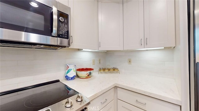 kitchen with backsplash, appliances with stainless steel finishes, and white cabinets