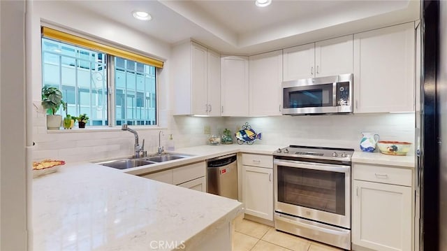 kitchen with light tile patterned flooring, sink, white cabinetry, stainless steel appliances, and decorative backsplash