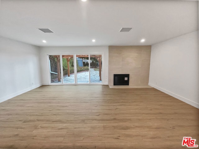 unfurnished living room with a large fireplace and light hardwood / wood-style flooring