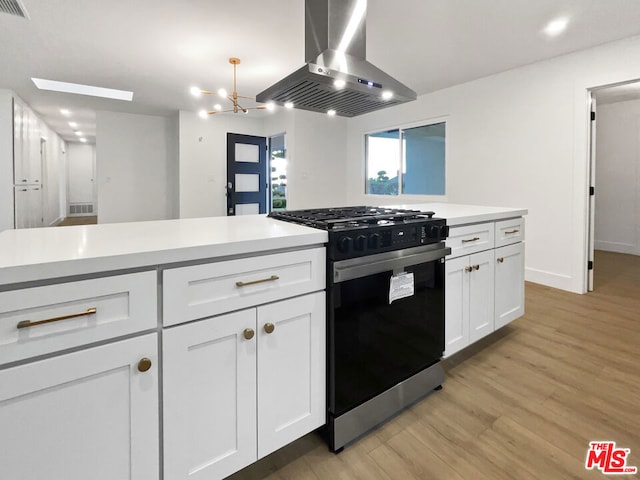 kitchen with white cabinetry, gas range, light hardwood / wood-style floors, and island exhaust hood