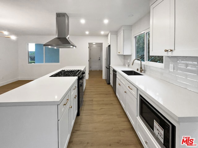 kitchen featuring island range hood, range with gas cooktop, white cabinetry, sink, and stainless steel fridge