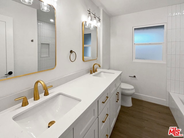 full bathroom featuring vanity, hardwood / wood-style flooring, toilet, and washtub / shower combination