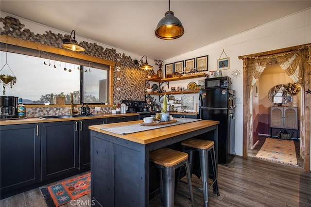 kitchen featuring sink, wooden counters, a kitchen breakfast bar, a kitchen island, and black appliances