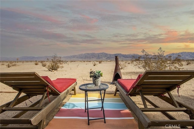 balcony at dusk with a mountain view and a patio area