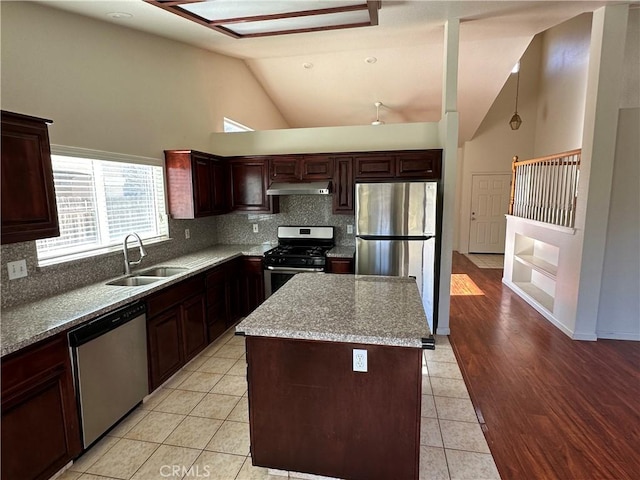 kitchen featuring sink, a center island, light tile patterned floors, appliances with stainless steel finishes, and light stone countertops