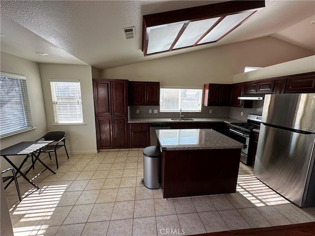 kitchen featuring a healthy amount of sunlight, stainless steel appliances, a center island, and light tile patterned floors