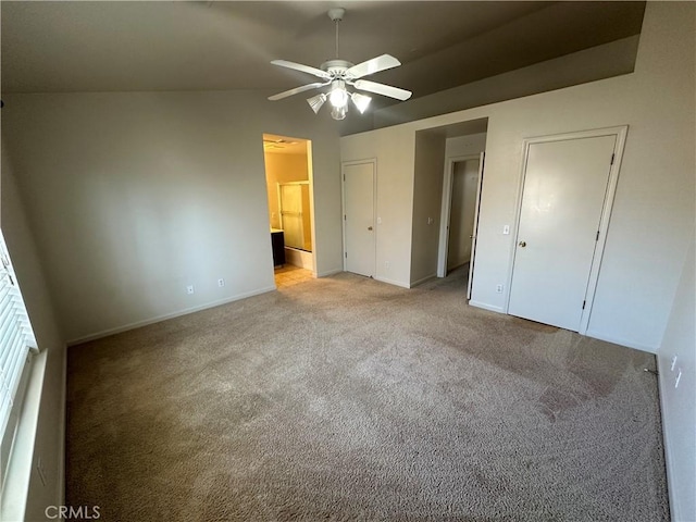 unfurnished bedroom featuring light colored carpet, ensuite bathroom, and vaulted ceiling