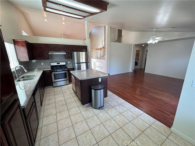 kitchen with sink, appliances with stainless steel finishes, tasteful backsplash, a kitchen island, and light tile patterned flooring