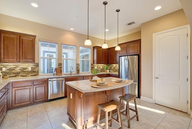 kitchen with light tile patterned flooring, sink, light stone counters, a center island, and appliances with stainless steel finishes