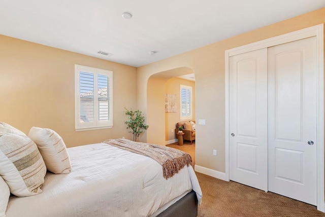 bedroom with multiple windows, a closet, and carpet