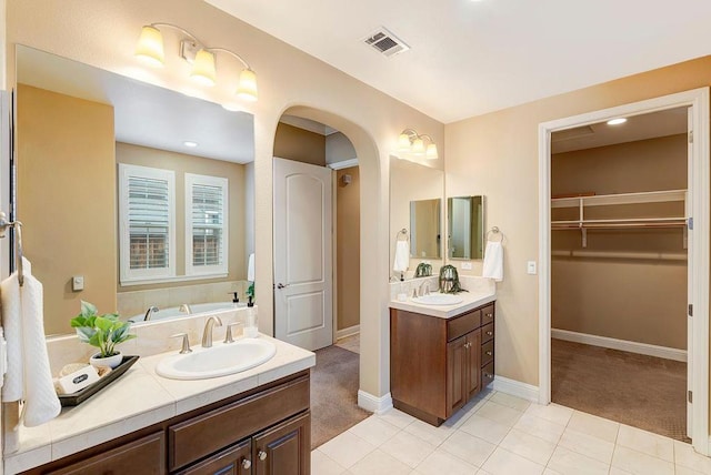 bathroom featuring vanity, a washtub, and tile patterned floors