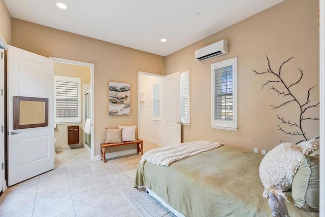 bedroom with light tile patterned floors, ensuite bath, and an AC wall unit