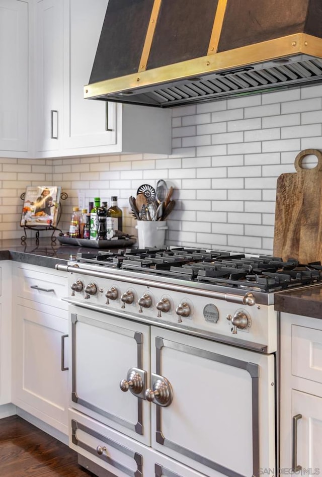 kitchen with tasteful backsplash, range hood, and white cabinets