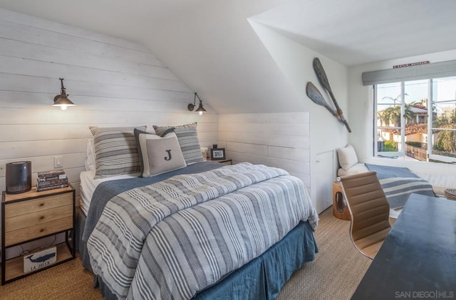 bedroom featuring carpet floors, wooden walls, and vaulted ceiling