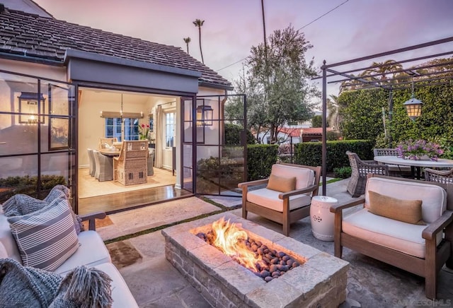 patio terrace at dusk with an outdoor living space with a fire pit