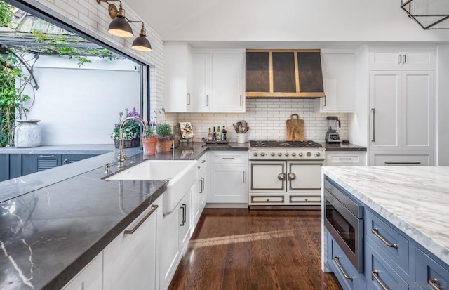 kitchen with sink, appliances with stainless steel finishes, white cabinetry, decorative backsplash, and dark stone counters