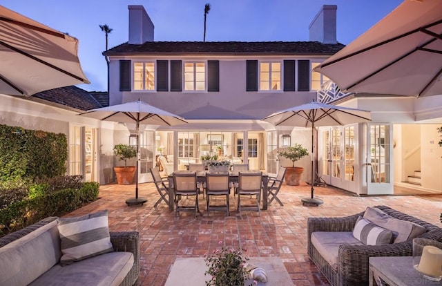 back house at dusk featuring a patio area