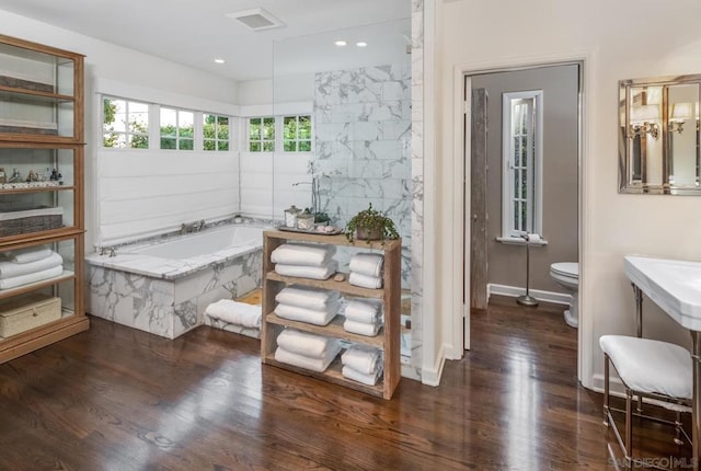 bathroom featuring hardwood / wood-style floors, tiled bath, and toilet