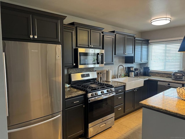 kitchen with light tile patterned flooring, stainless steel appliances, sink, and stone counters