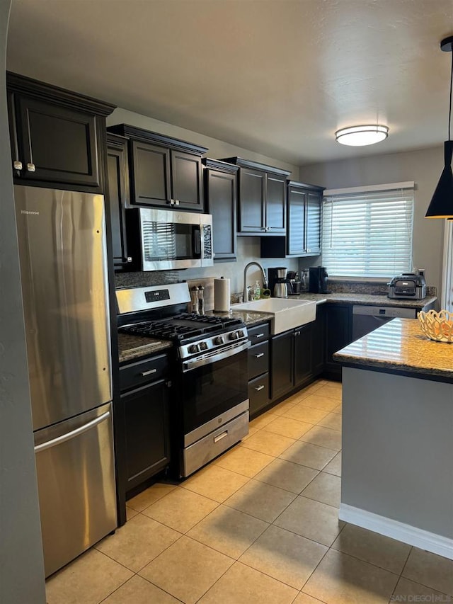 kitchen with sink, light tile patterned floors, appliances with stainless steel finishes, hanging light fixtures, and light stone countertops