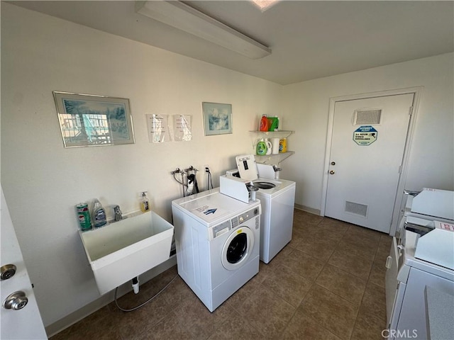 laundry area featuring sink, washing machine and dryer, and dark tile patterned floors